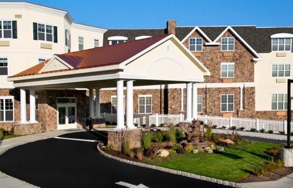 Exterior view of the front of The Bristal Assisted Living at Woodcliff Lake with covered driveway and entrance and manicured lawn