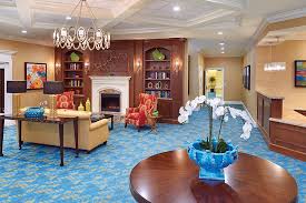 The Bristal at Lake Success lobby with sitting area around a fireplace and stocked book shelves
