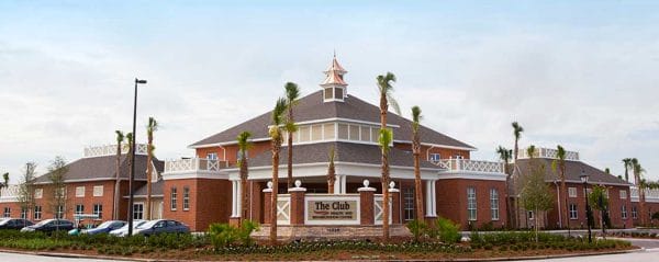The Club and Rehabilitation Center at The Villages sign surrounded by palms with the building behind