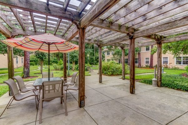 Outdoor trellis with a umbrella covered picnic table in the courtyard of The Cove at Marsh Landing