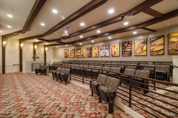 Stadium seats and wall art in the theater room at American House Coconut Point