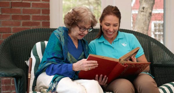Visiting Angels of Venice caregiver looking at photo album with senior woman