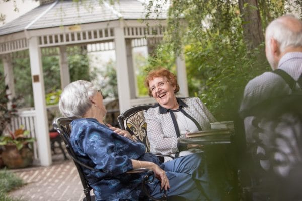 Two senior women laging while seated outdoors at Windsor Place at Orlando Lutheran Towers