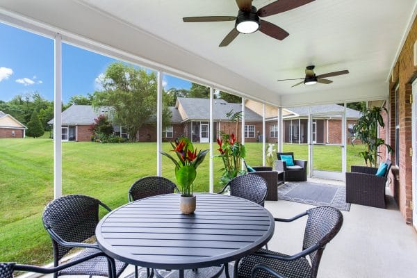 Outdoor dining table and resident lounge area on the Charter Senior Living of Hermitage back porch