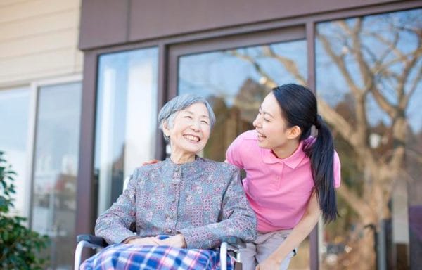 Assisted Care Services laughing with elderly woman in wheelchair