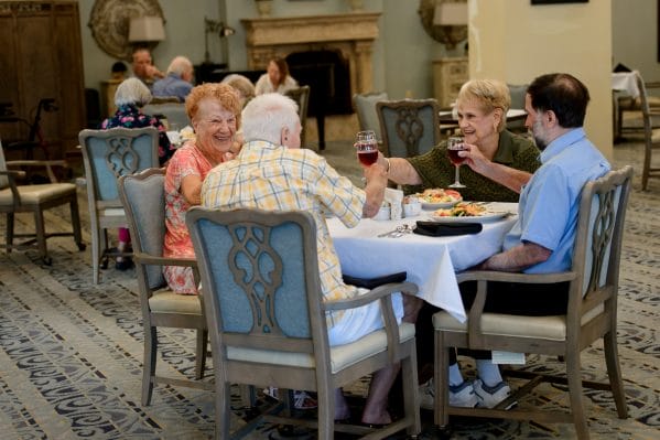 Residents enjoying a glass of wine with dinner at American House Bluewater Bay