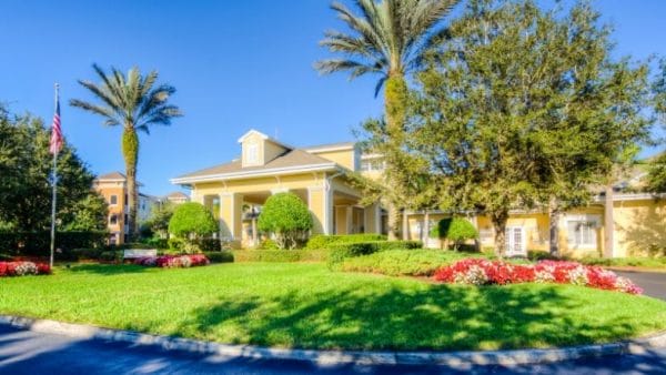 Front of building with flowers, shrubs and palm trees at Aston Gardens at Tampa Bay