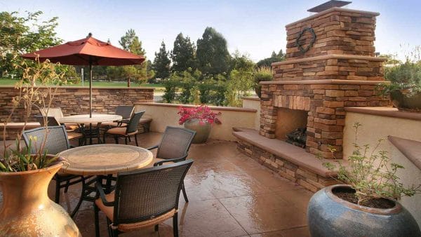 Oudoor stone fireplace and residnt dining tables on the Atria Las Posas patio