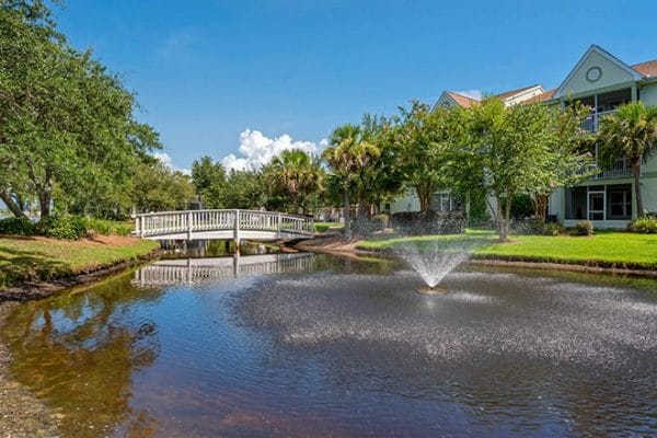 Walking bridge over a pond with a water fountain on the grounds of Brookdale Destin
