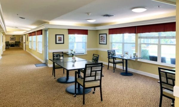 Community dining area with tables and chairs with windows at Lassen House Senior Living