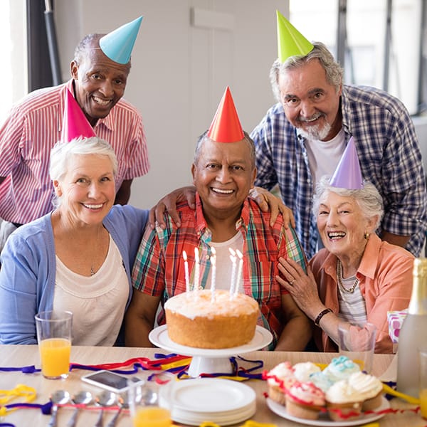5 seniors wearing birthday hats over cake at The Pointe