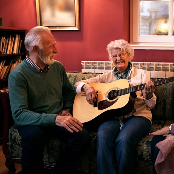 Senior residents of The Pointe with woman playing guitar