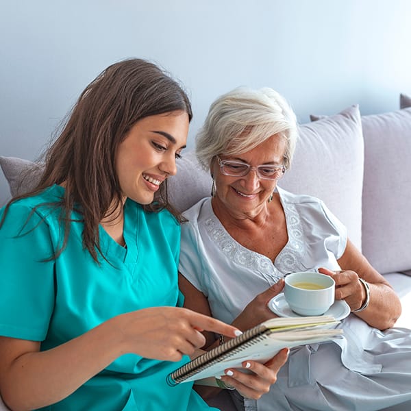 The Pointe caregiver reading to senior woman in bed