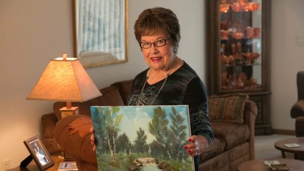Senior resident of Maple Ridge Retirement proudly showing her artwork