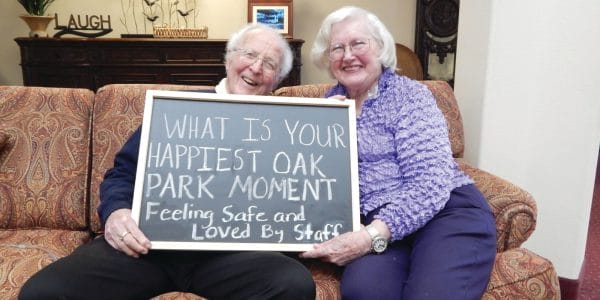 Two Oak Park Retirement residents holding a chalkboard that asks what your happiest moment at Oak Park is