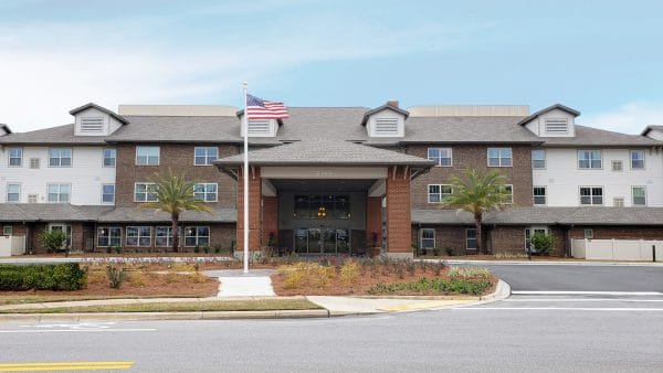 Front entrance view of Red Hills Village Retirement with large covered driveway and American flag in front