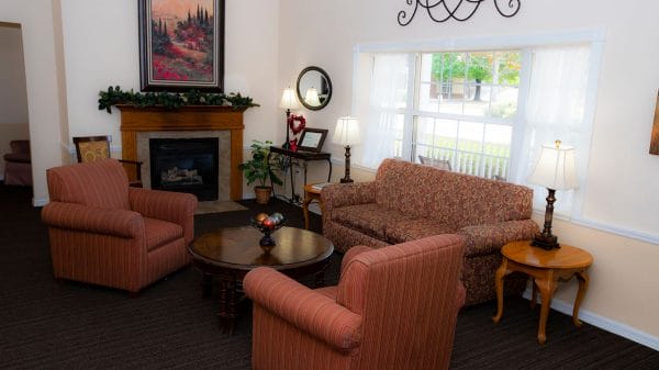 Resident living room with overstuffed chairs and couch in front of fireplace at Savannah Cottage of Oviedo I and II
