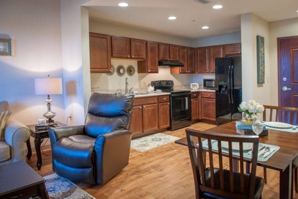 Apartment interior at Seagrass Village of Fleming Island with arm chair and table and kitchen in background