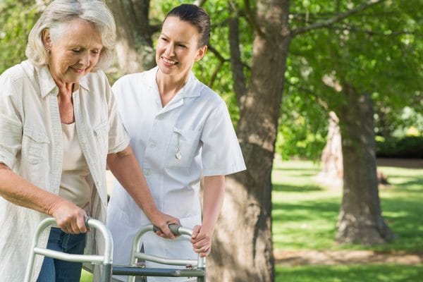 Hand 'N Heart caregiver assisting senior woman in walker