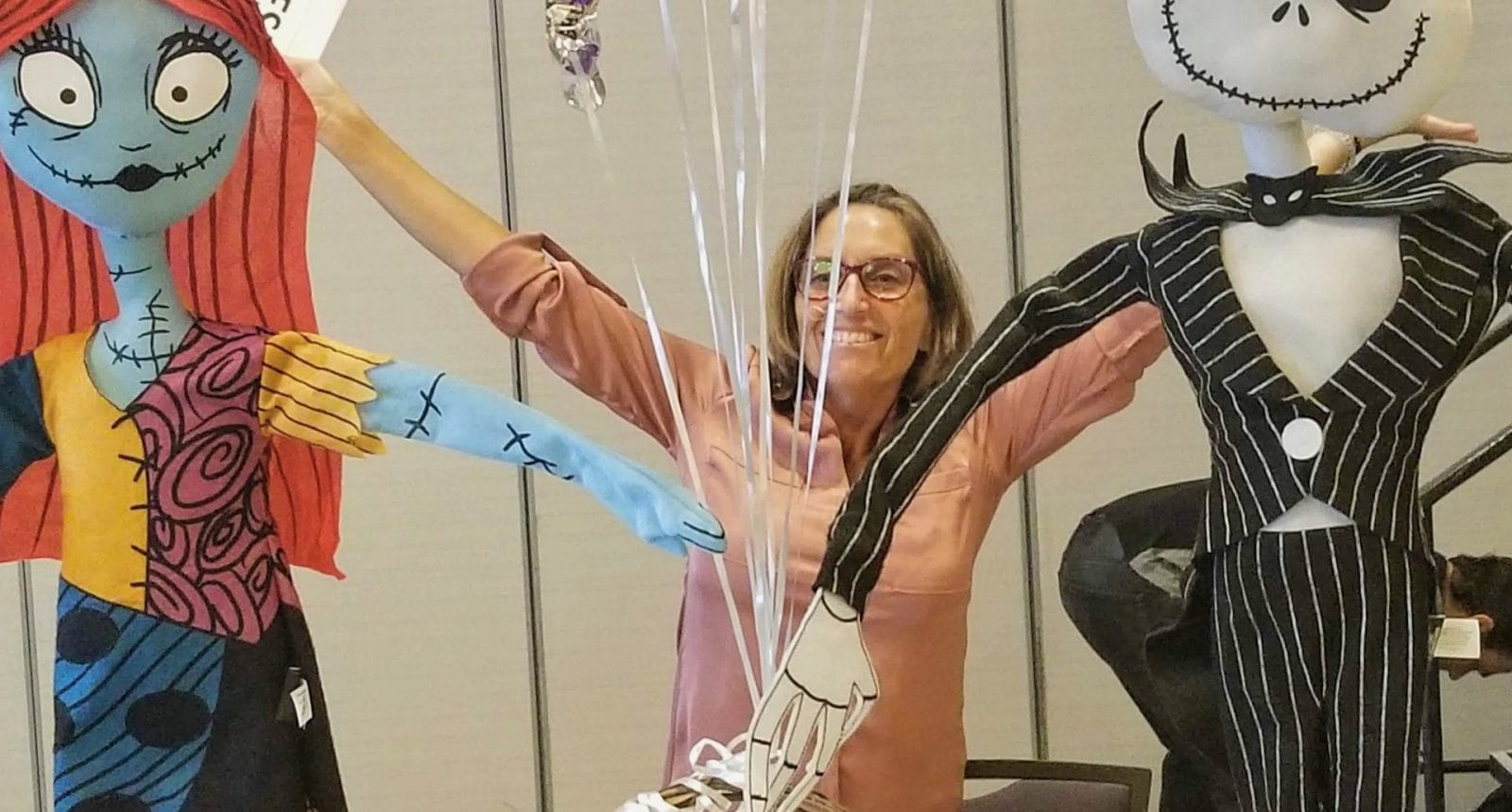 Female social worker with balloons and arms raised