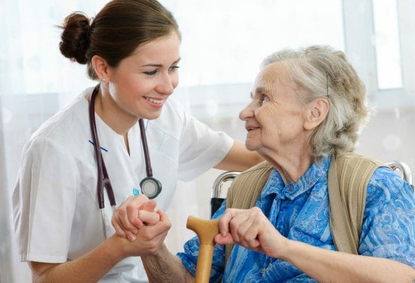 Senior woman with cane holding hands with Touched by Angels Home Healthcare II caregiver