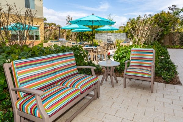 Stripped cushioned chairs and resident seating on the The Club at Boynton Beach patio