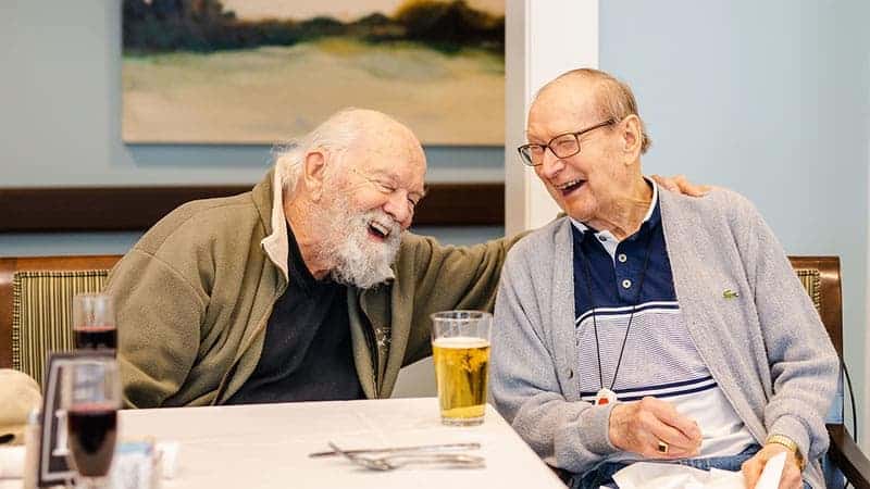 senior men laughing and talking over drinks during happy hour