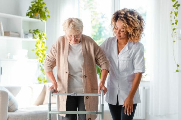 Compassionate Care female caregiver assisting woman in walker