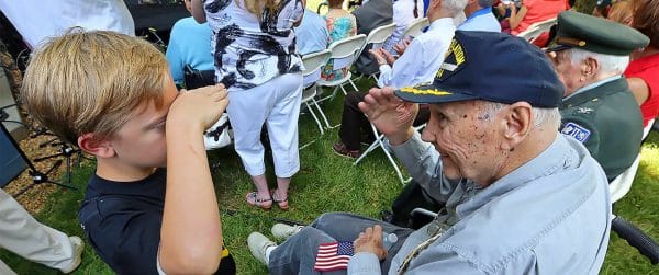 Young boy saluting a senior veteran man in a cap