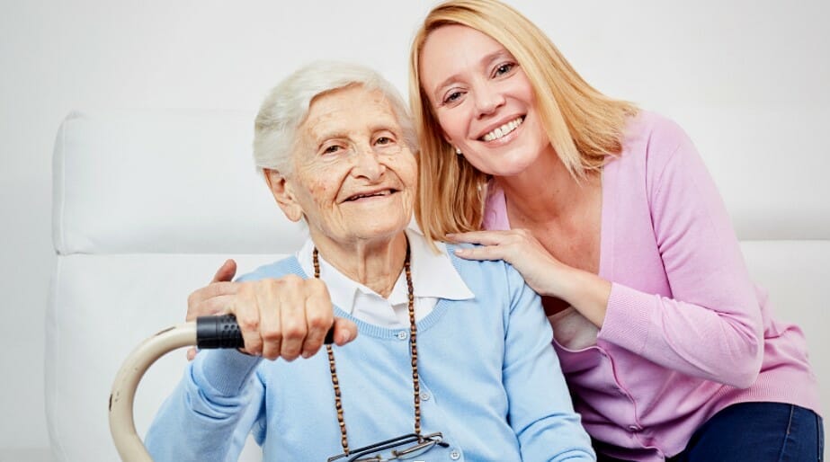 Young woman with her arms on the shoulders of a senior woman and both are smiling
