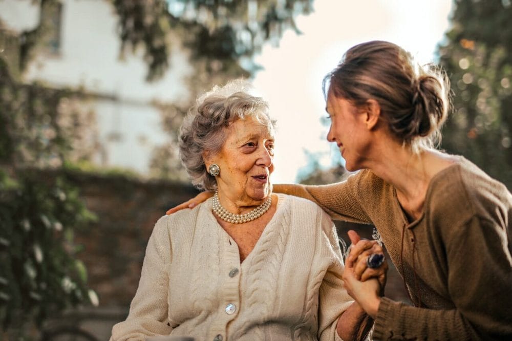 Woman with her arm around a senior woman and smiling and discussing Declutter tips for seniors 