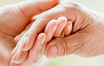 Excellence Home Health caregiver holding hands with client