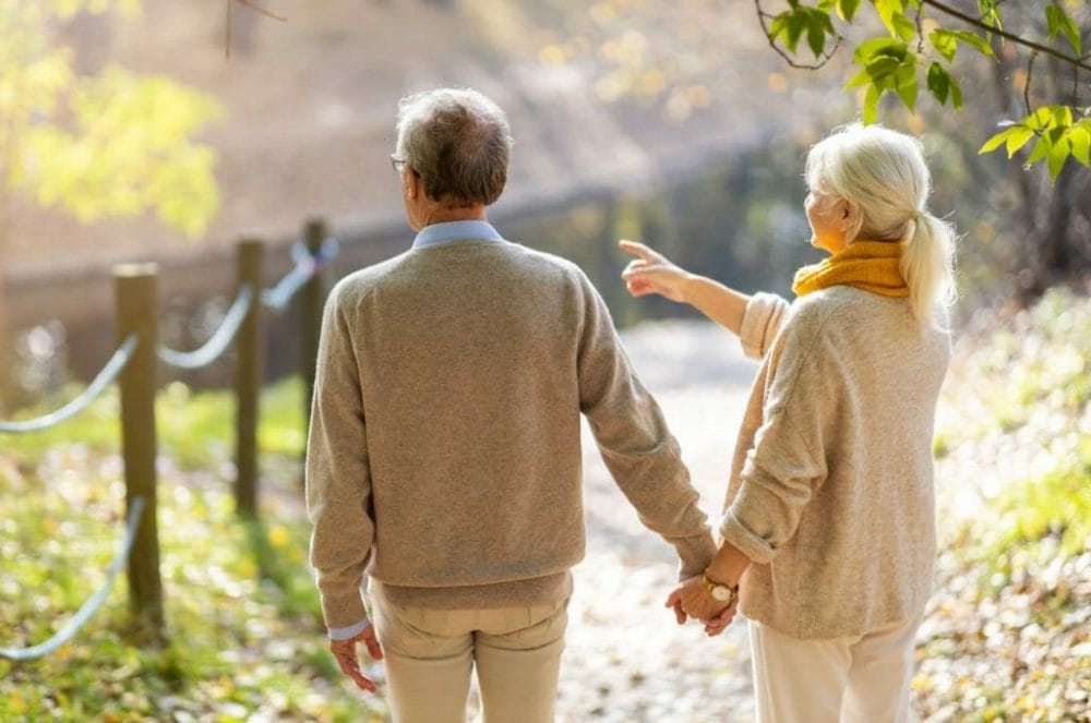 Senior man and woman holding hands outdoors