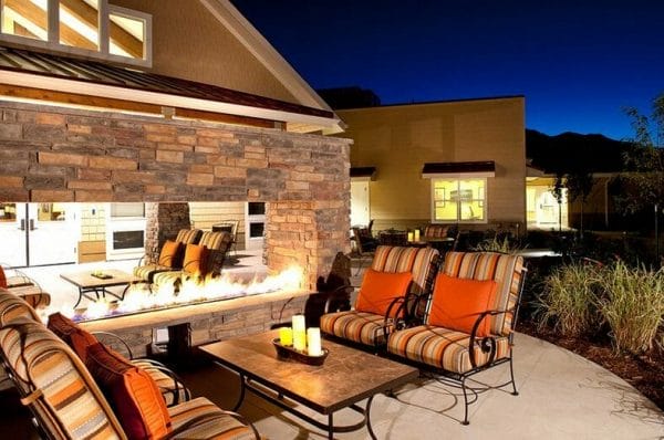 Outdoor seating by a fireplace on the MorningStar Memory Care at Bear Creek patio at dusk